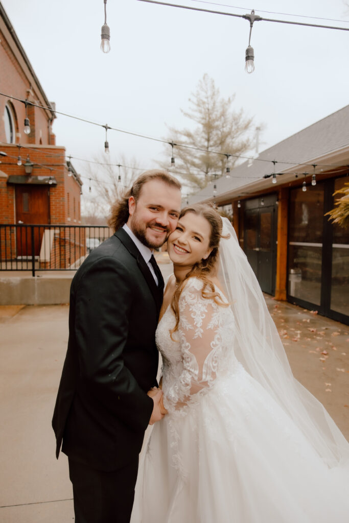 Couple looking at camera smile with there checks touching together.