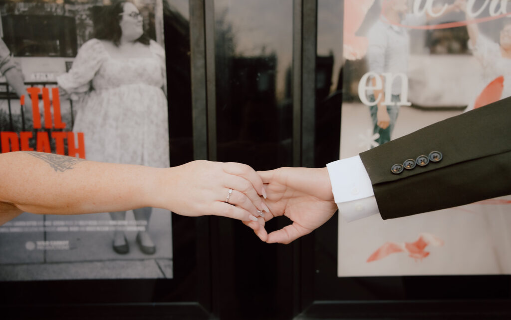 Bride and groom holding hands in-front of movie posters 