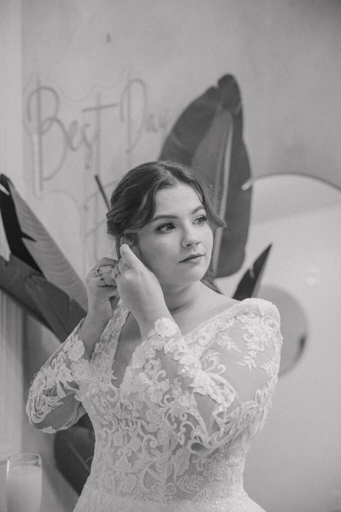 Bride putting on her earrings in the getting ready room at wedding venue.