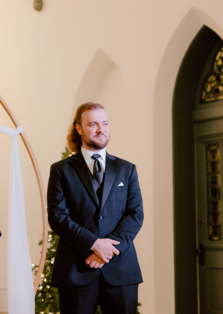 Groom looking at the bride as she walking down aisle.